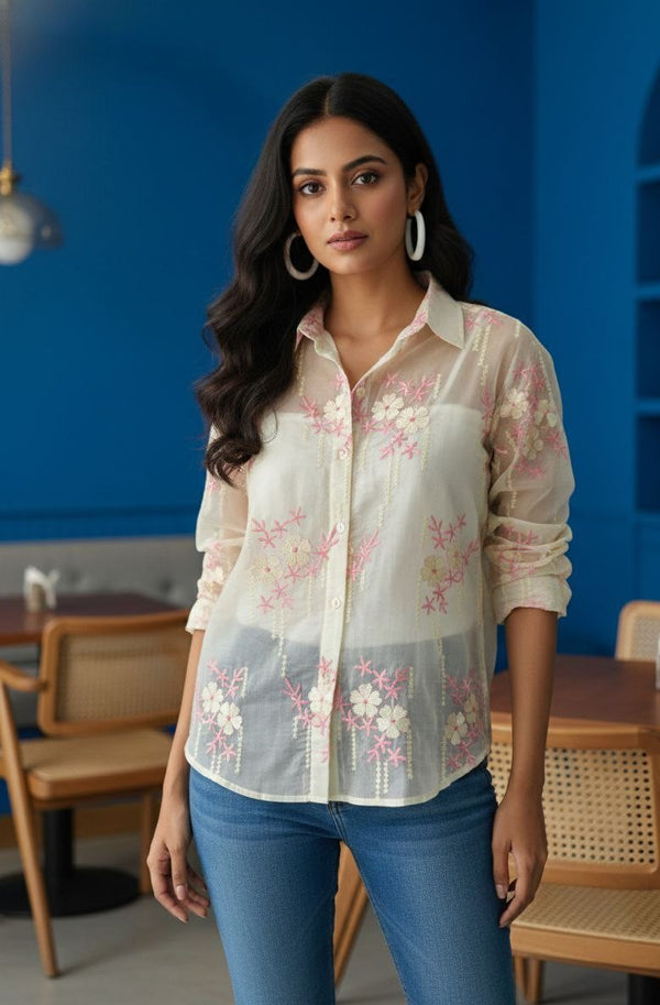 Woman wearing a floral blouse and blue jeans in a casual setting.