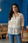 Woman wearing a floral blouse and blue jeans in a casual setting.